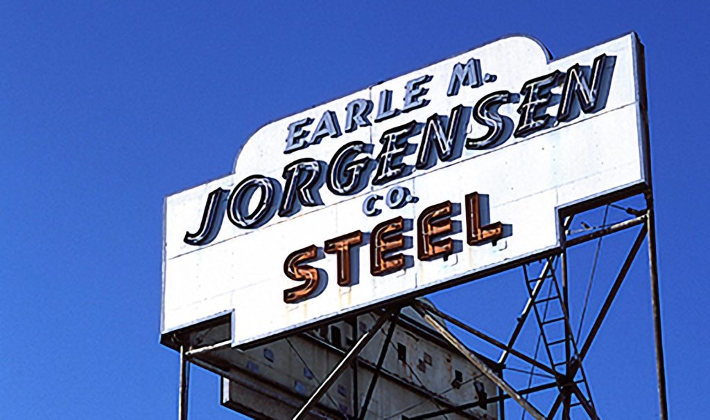 Vintage Earle M. Jorgensen Co. steel company sign against a blue sky.