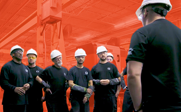 Group of industrial workers in hard hats meeting on a manufacturing floor